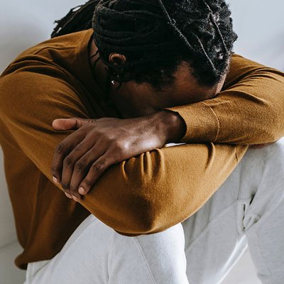 man sitting on floor with head down on arms struggling with anxiety