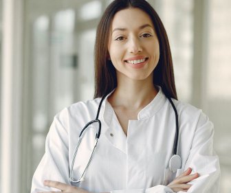 female doctor with stethoscope around neck, arms crossed, smiling