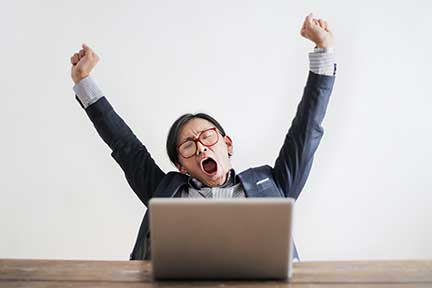 tired worker yawning at a laptop