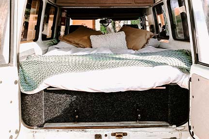 RV sleeper sofa in back of RV with brown and white pillows on top